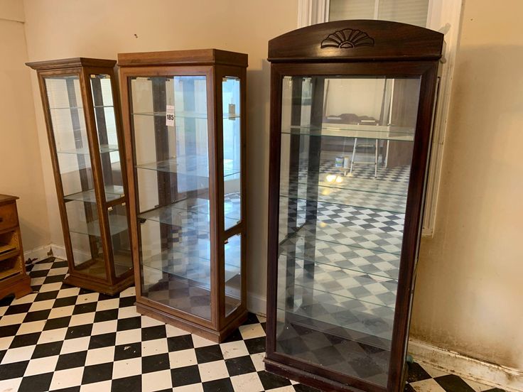 three glass cases sitting on top of a black and white checkered floor next to each other