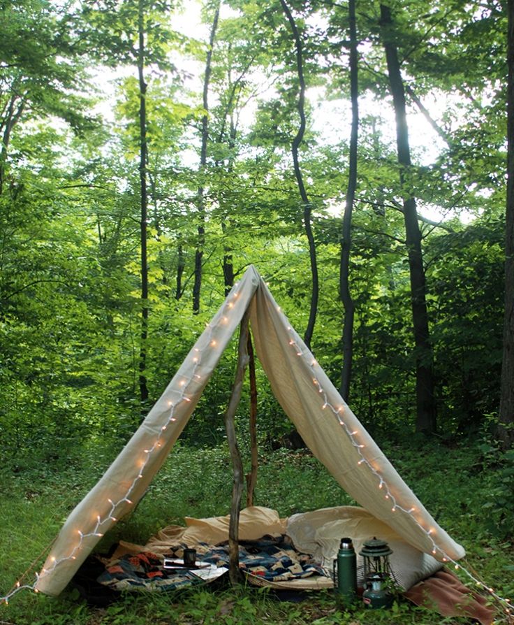 a tent in the woods with fairy lights on it