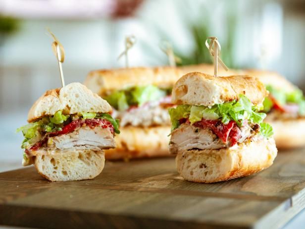 two sandwiches cut in half sitting on top of a cutting board with toothpicks