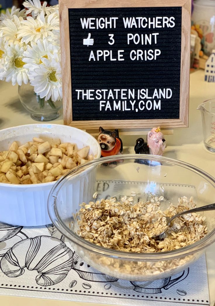 a table topped with bowls filled with oatmeal next to a sign that says weight watchers 3 point apple crisp