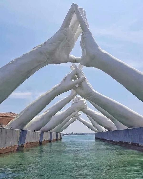 there are many hands reaching out to touch the water in front of an art installation