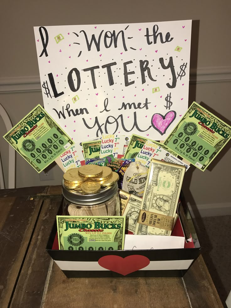 a gift box filled with money sitting on top of a table next to a sign that says i won the lotery when i met you