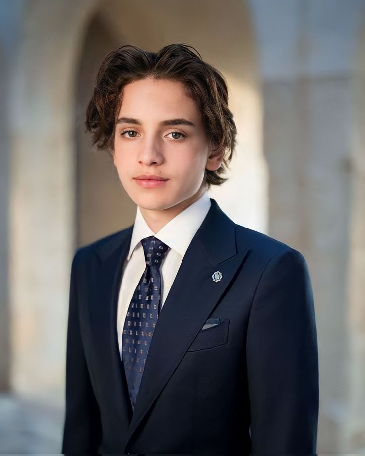 a young man in a suit and tie posing for a photo with an arch in the background