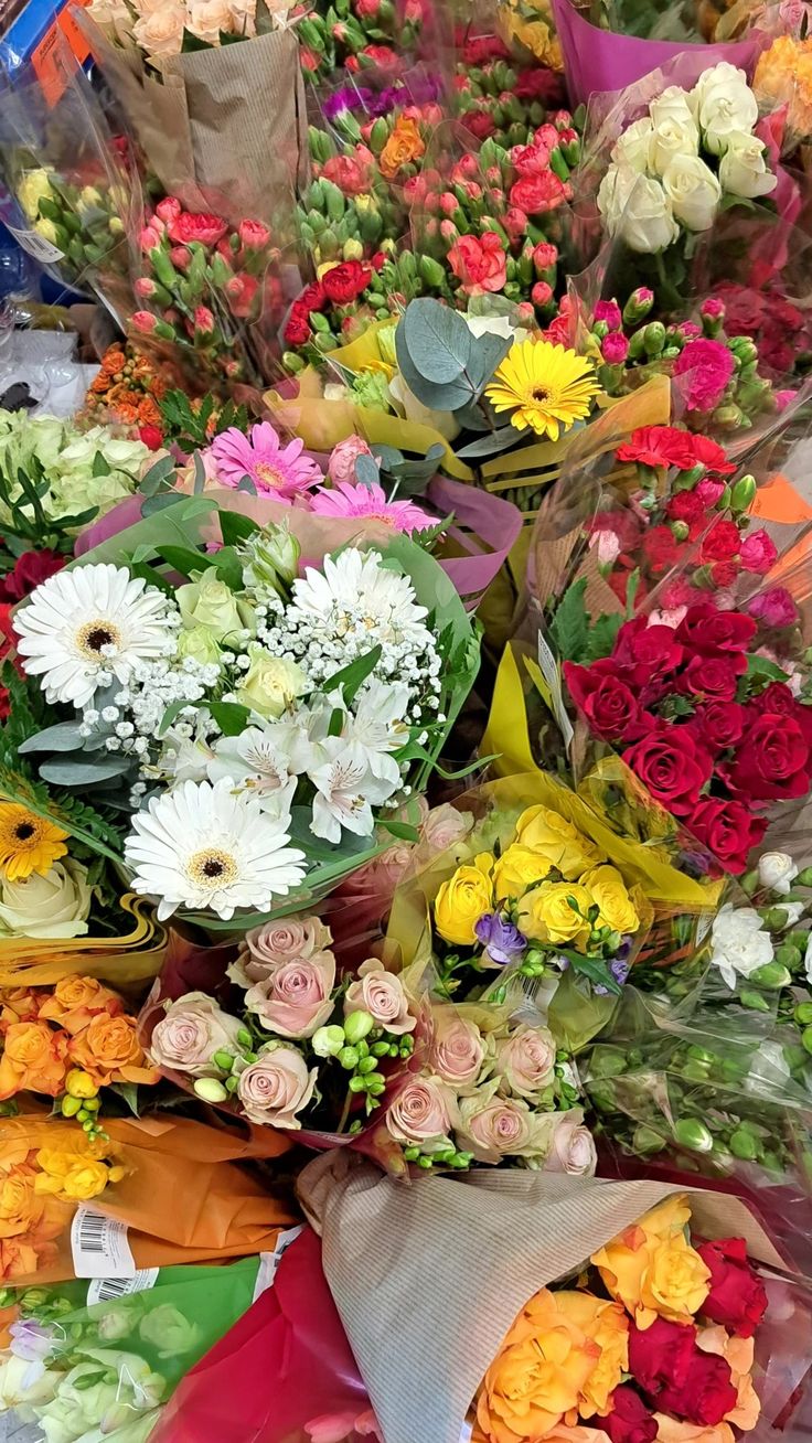 a bunch of flowers that are laying on the ground next to each other and wrapped in paper