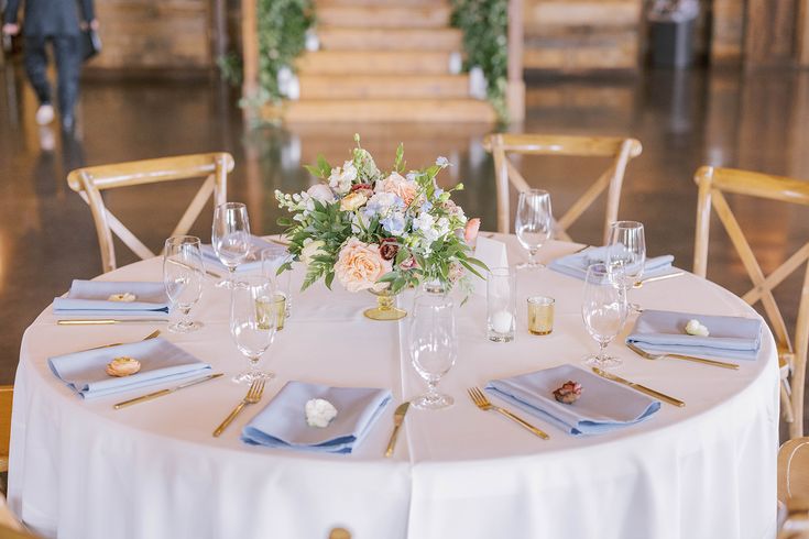 the table is set with white linens and gold place settings for an elegant wedding reception