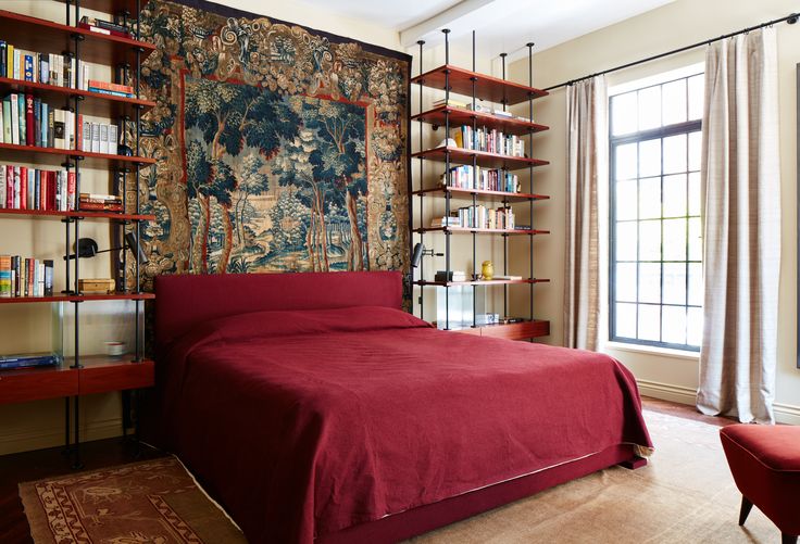 a bedroom with a red bed and bookshelves