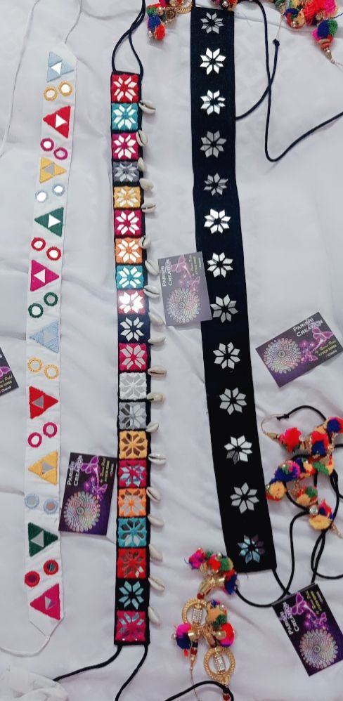 several bracelets are laid out on a white sheet with colorful beads and decorations around them