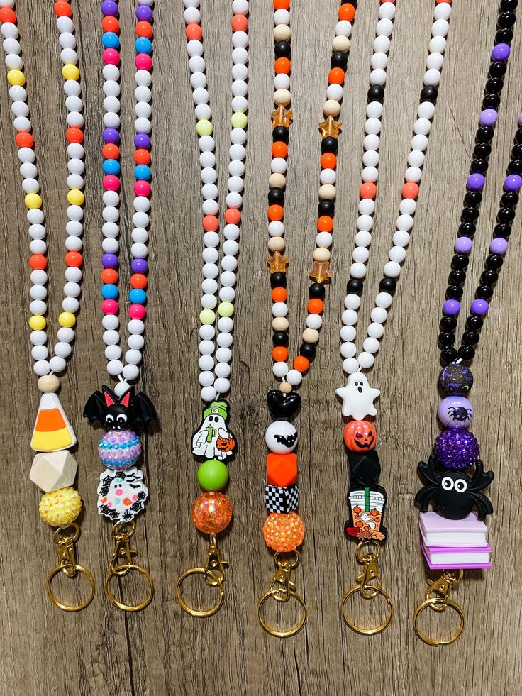 several key chains are lined up on a wooden surface, each with different designs and colors