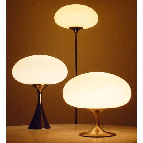 two lamps sitting on top of a table next to each other in front of a brown wall