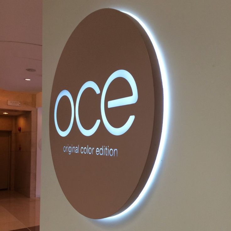 the entrance to an office building with a circular sign that reads oce and is lit up