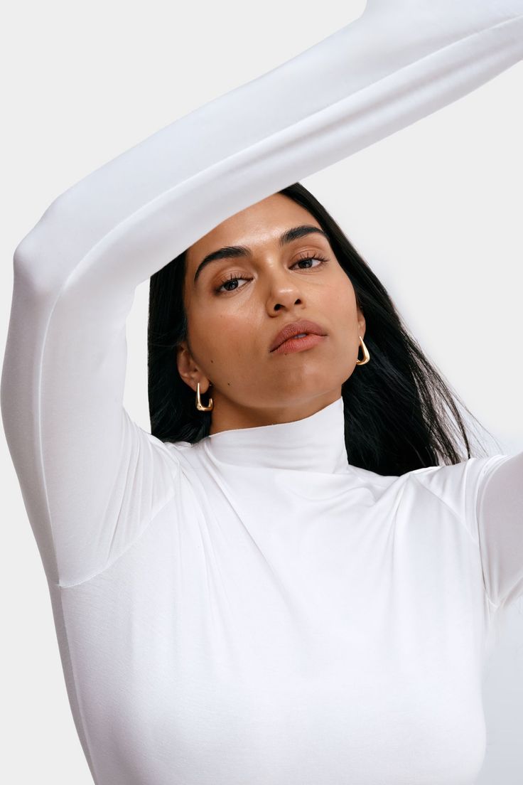 It’s our Ilana Top’s contemporary subtlety that makes her so outfit-changing. This long-sleeve top is crafted from soft, high-stretch and sustainable European jersey to mold perfectly and comfortably to your form. Her showpiece? The diagonal, raw-edged neckline, elevating a classic mock-neck design to a unique day-to-night essential. | Sejal, in off white, is 5'8" (173 cm) tall, wearing size M. Astrid, in off white, is 5'9" (175 cm) tall, wearing size XS. Yada, in mist, is 5'9" (175 cm) tall, we Spring Elegant Long Sleeve Mock Neck Top, Elegant Spring Long Sleeve Mock Neck Top, Elegant Long Sleeve Mock Neck Top For Spring, Long Sleeve Tops With Thumbholes, Long Sleeve Tops With Thumbholes And Minimal Stretch, Versatile Long Sleeve Mock Neck Top For Layering, Long Sleeve Top With Thumbholes And Minimal Stretch, Versatile Long Sleeve Top With Thumbholes For Spring, Long Sleeve Tops For Layering With Minimal Stretch