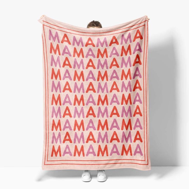 a pink and red blanket with the word mama printed on it, in front of a white wall