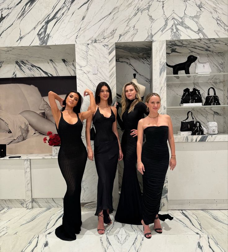 three beautiful women standing next to each other in front of a marble wall and shelves