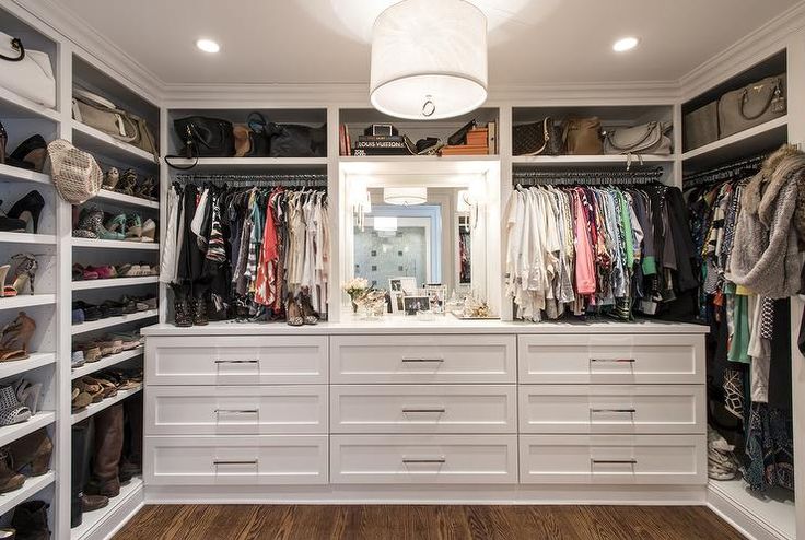 a walk in closet filled with lots of white drawers and clothes on top of shelves