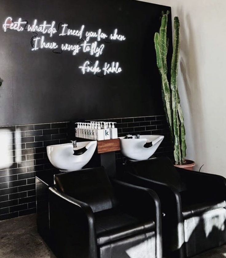 two black chairs sitting in front of a wall with writing on it and a potted plant