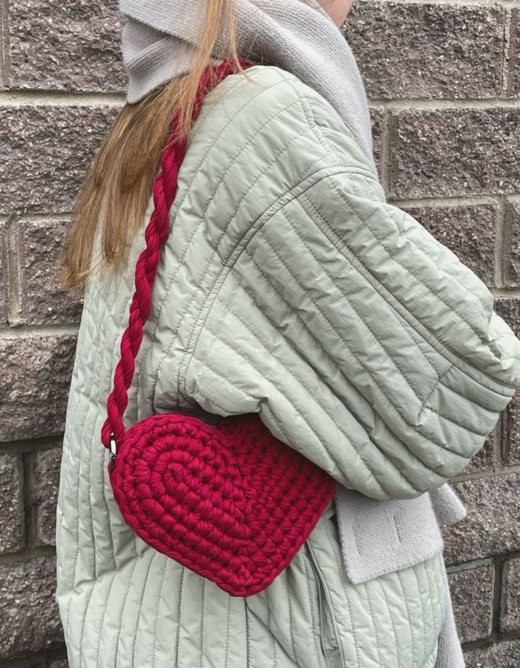 a woman wearing a gray jacket carrying a red handbag on her back with braided handles