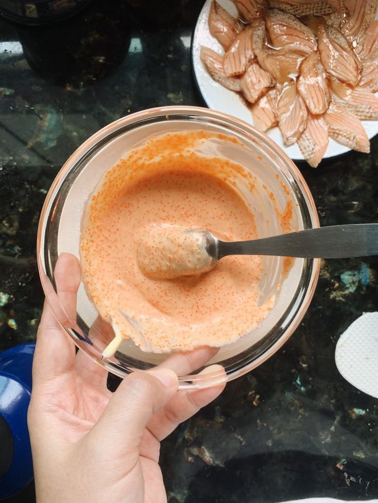 someone is mixing something in a glass bowl