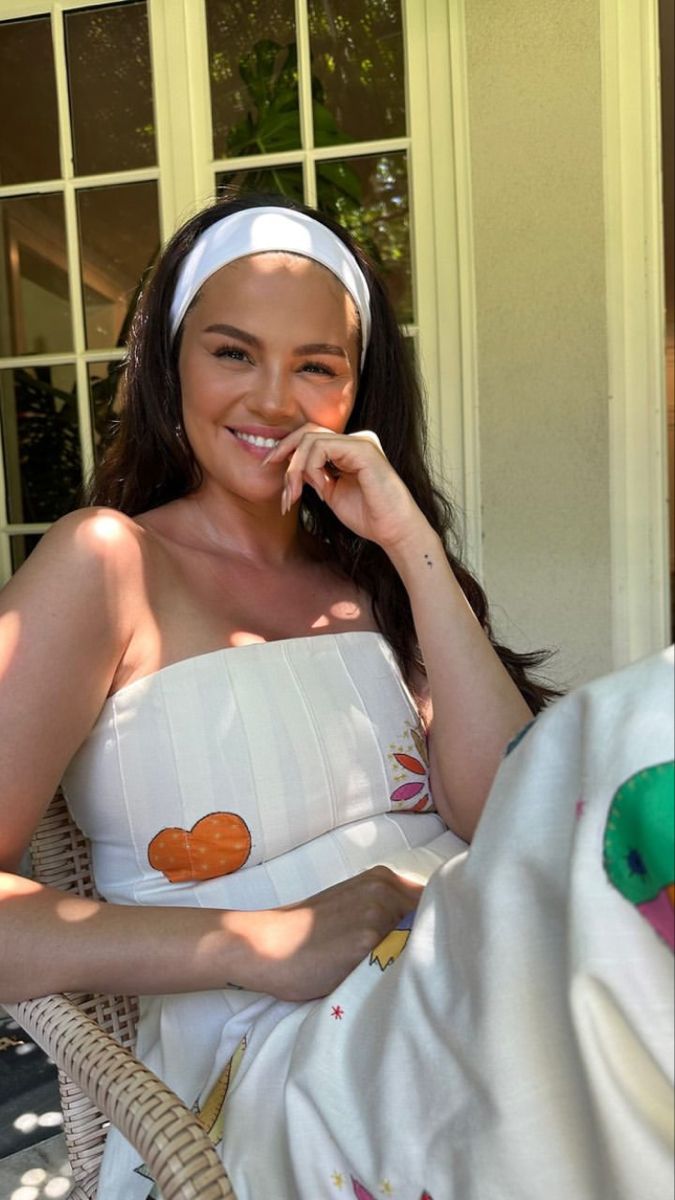 a woman sitting in a chair with a towel over her head and an orange on it