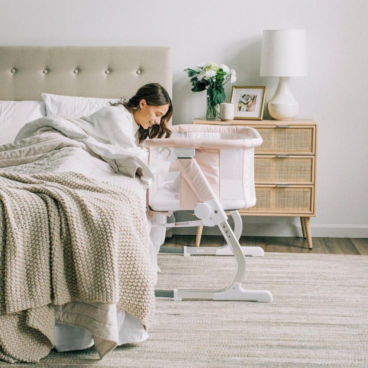 a woman laying in bed next to an ironing board