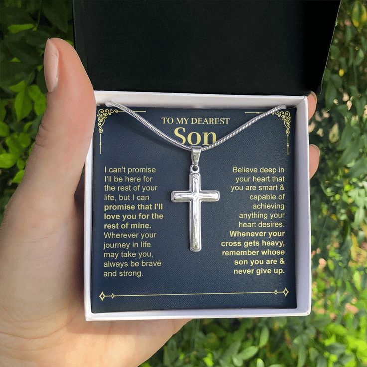 a person holding up a silver cross necklace in their hand with an inspirational poem on it