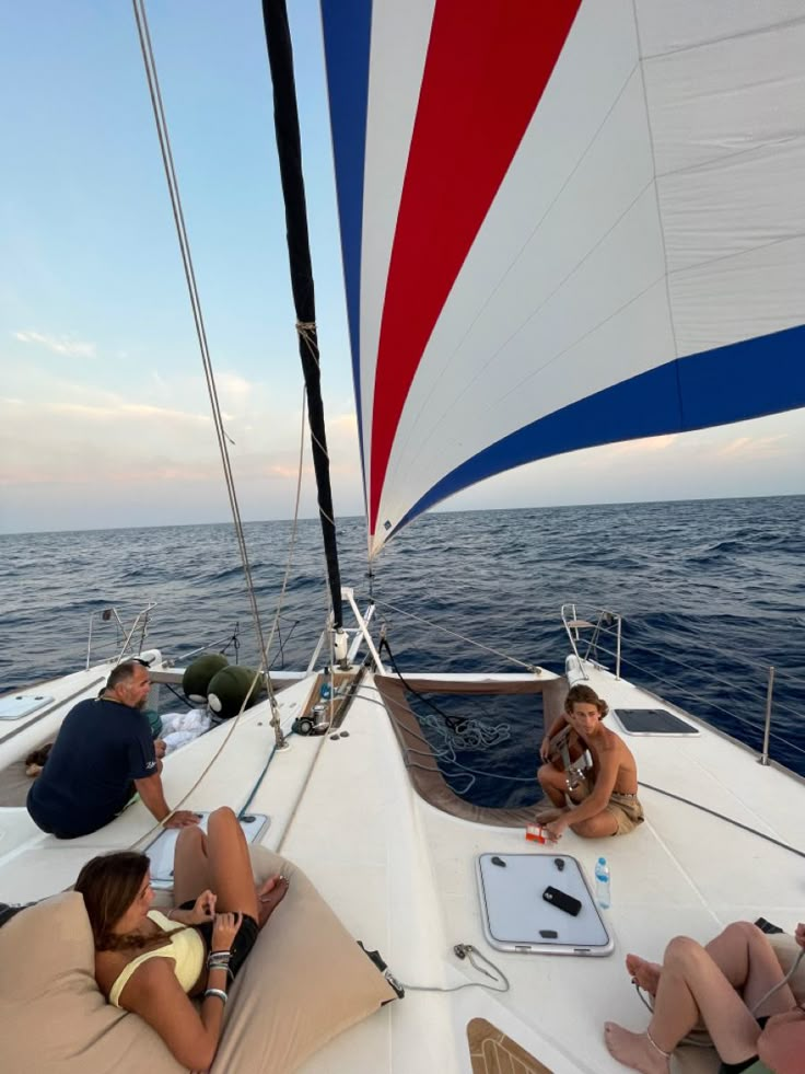 people sitting on the back of a sailboat in the ocean