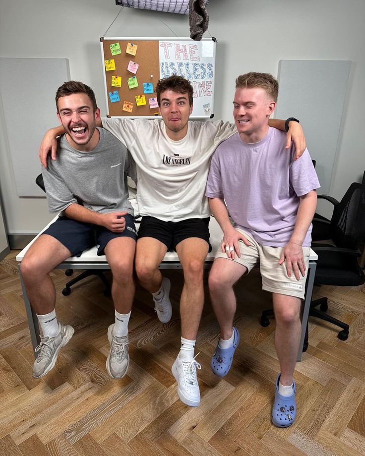 three men are sitting on a chair with post - it notes attached to their backs