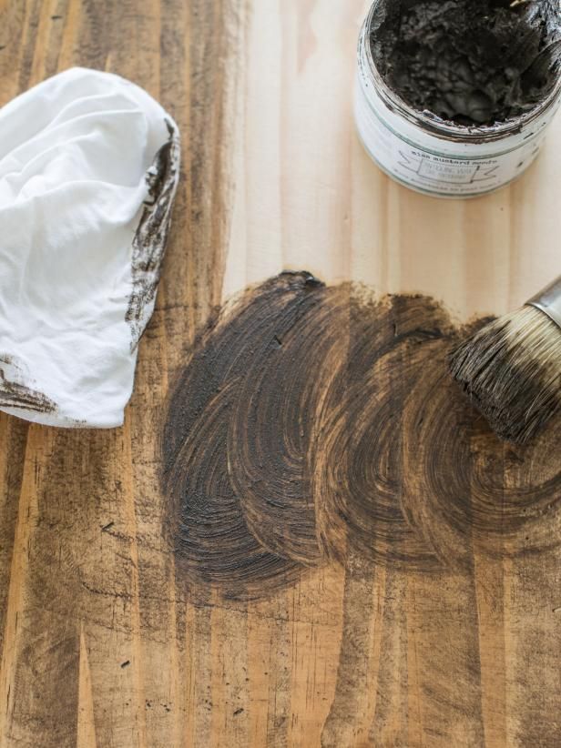 a wooden cutting board with some paint and a brush on it next to a container of dirt