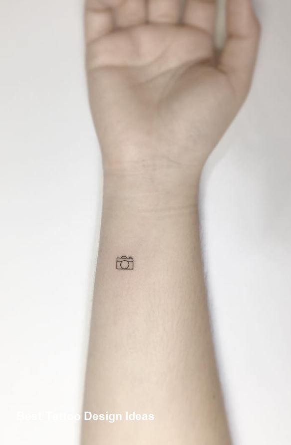 a person's arm with a small camera tattoo on the left side of their wrist