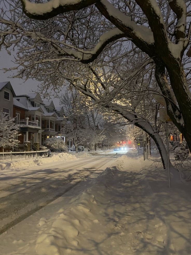 a snow covered street with houses in the background