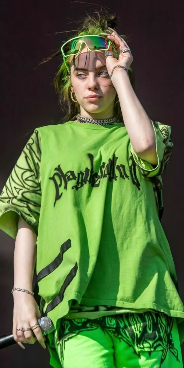 a woman with green hair and sunglasses on her head is holding a stick in front of her face