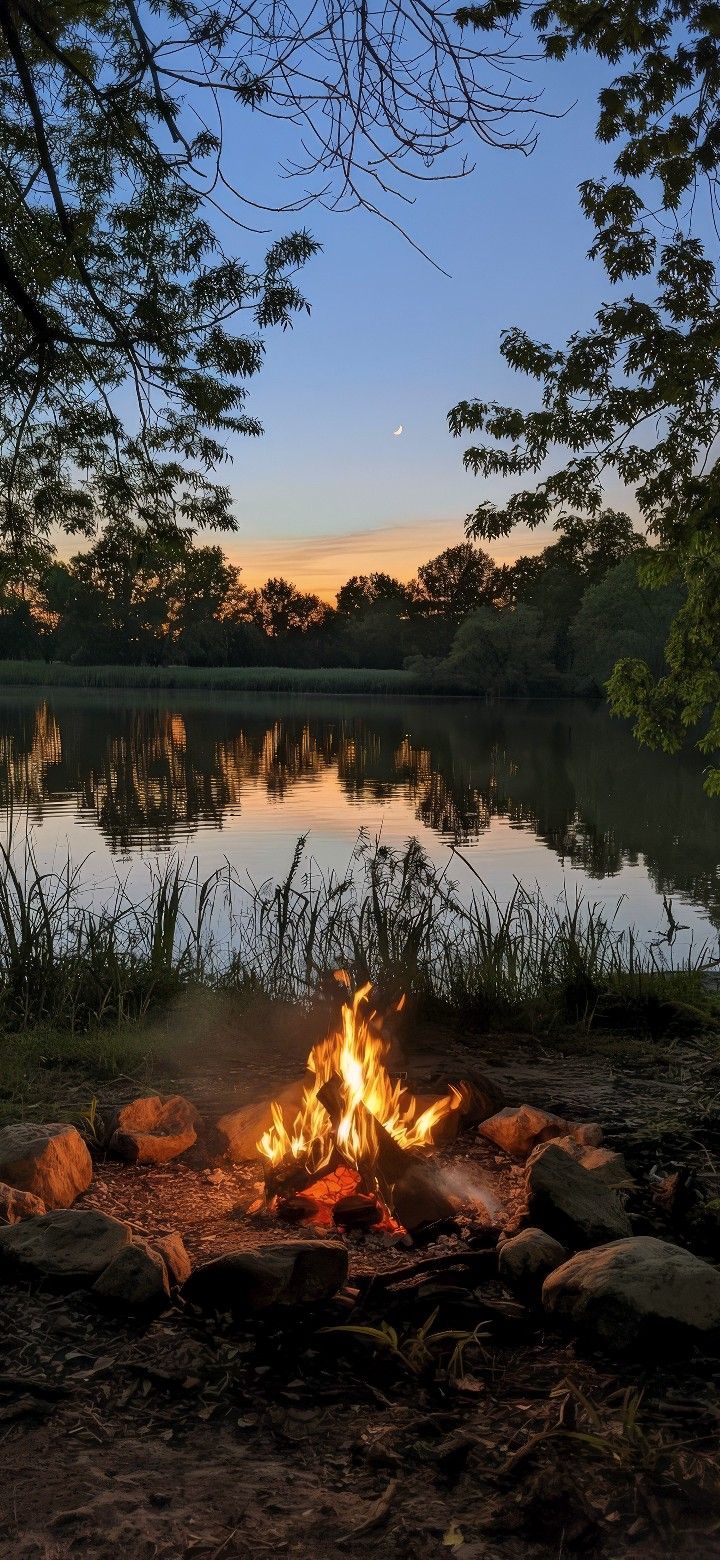 a campfire in front of a lake at sunset