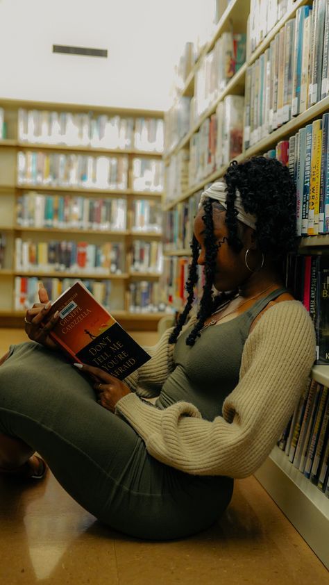 a woman sitting on the floor in front of a book shelf with bookshelves