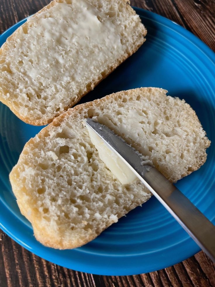 two pieces of bread on a blue plate with a knife and butter spread over it