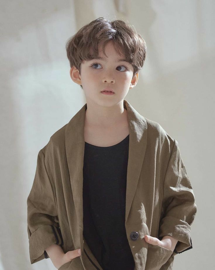 a young boy wearing a brown jacket and black shirt