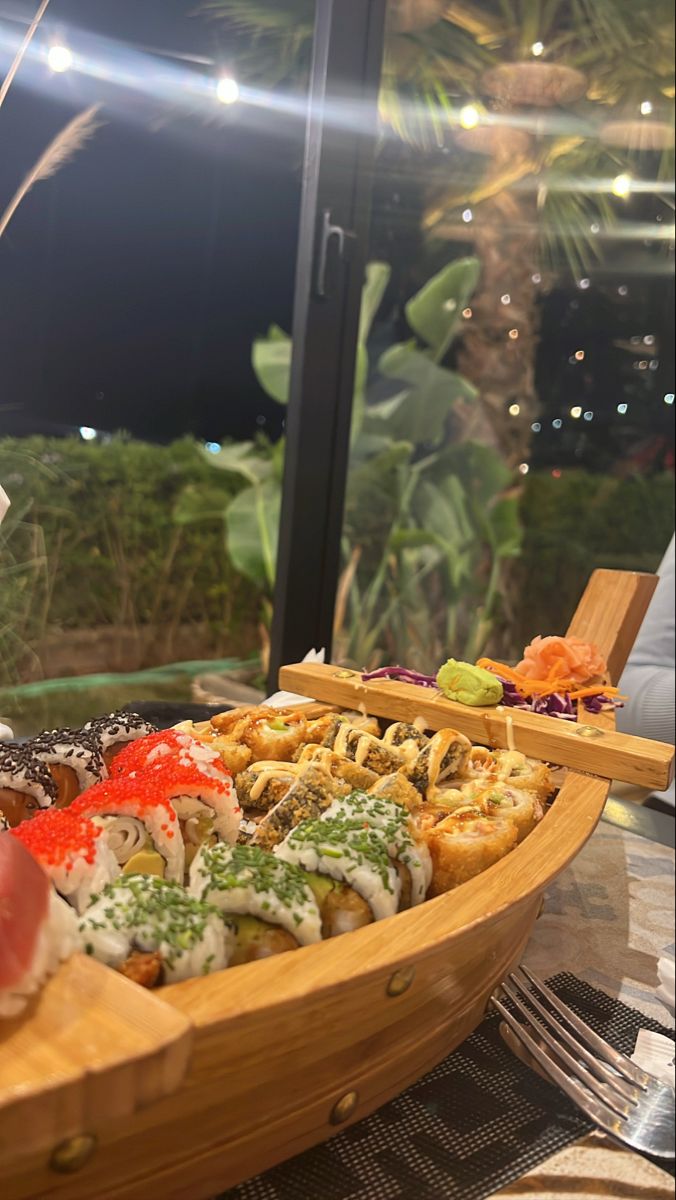 a wooden boat filled with lots of different types of food on top of a table