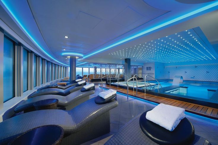 an indoor swimming pool with lounge chairs and blue lighting