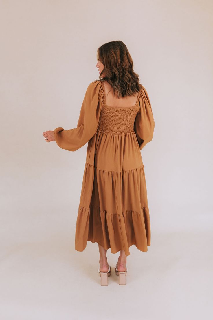 Get ready to fall head over heels for our Falling Faster Dress! This caramel-colored dress features delicate lace detailing and a charming tied bow on the front of the bodice. The smocked panel in the back ensures a comfortable and flattering fit, while the tiered skirt adds a whimsical touch. Complete with long, slightly puffed sleeves and a midi length, this dress also boasts a lace-trimmed neckline for an extra feminine touch. You'll be turning heads and feeling fabulous in this stunning dres Casual Dress With Smocked Back For Gatherings, Fall Square Neck Dress With Smocked Back, Brown Bohemian Dress With Square Neck, Brown Bohemian Square Neck Dress, Chic Fall Dress With Smocked Back, Casual Fall Midi Dress With Smocked Back, Fall Daywear Midi Dress With Smocked Back, Fall Dress With Smocked Bodice For Day Out, Fall Day Out Dress With Smocked Bodice