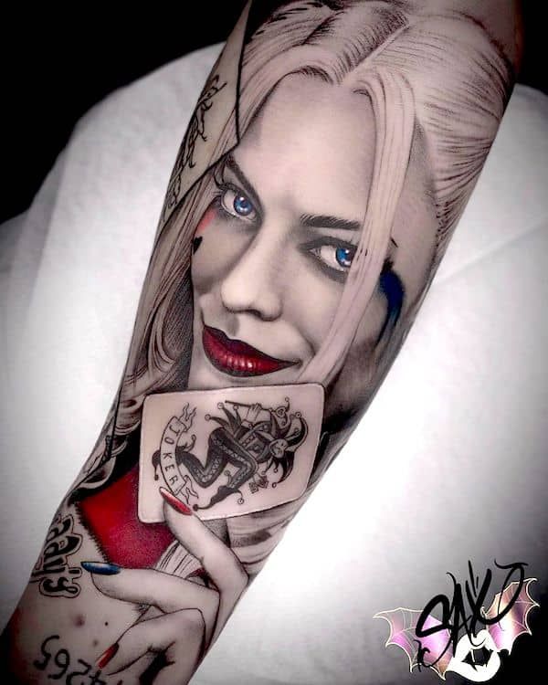 a woman with blue eyes holding a playing card tattoo on her forearm and arm,