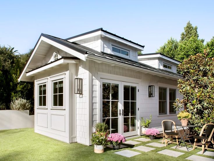 a small white house sitting on top of a lush green field