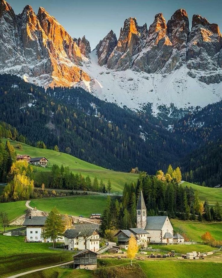 the mountains are covered in snow and green grass, with houses on either side of them