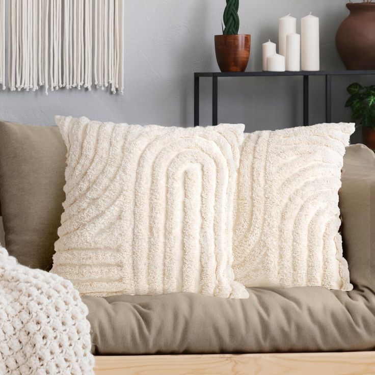 a couch with two pillows on top of it next to a table and potted plants