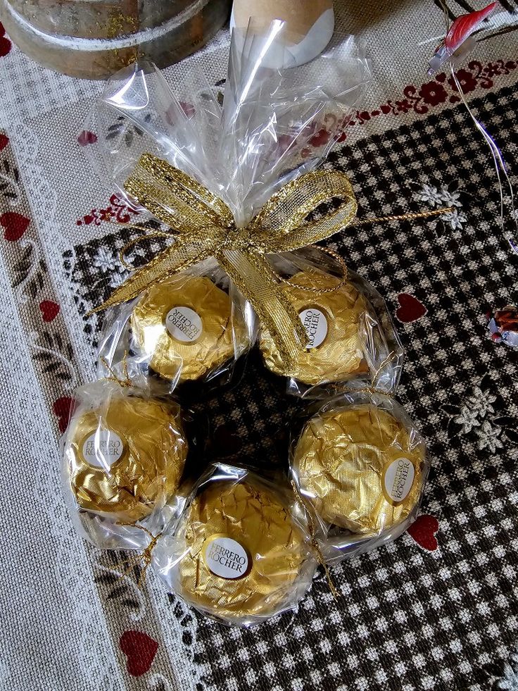 chocolates wrapped in cellophane and tied with gold ribbon on top of a table