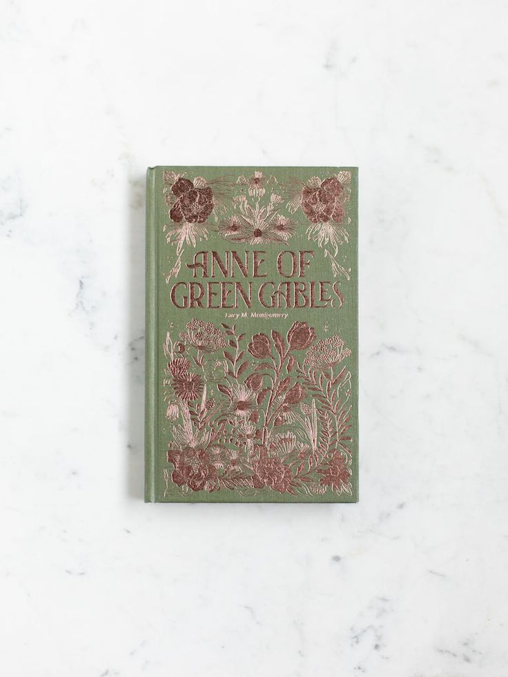 the front cover of an antique book with flowers and plants on it, against a white marble background