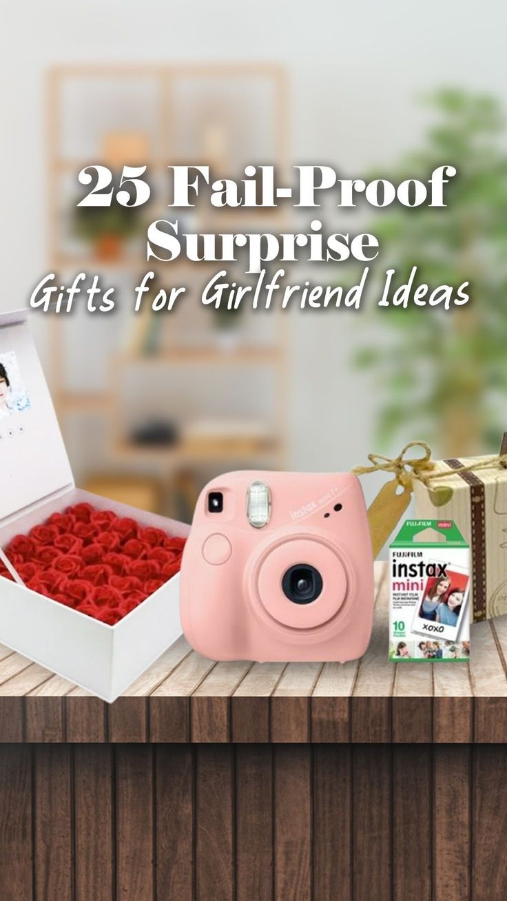 a pink camera sitting on top of a wooden table next to a box filled with red roses