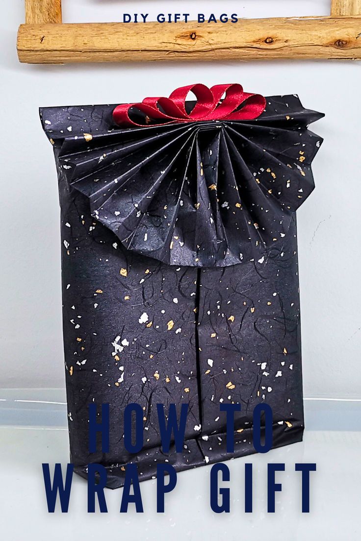 a black gift bag with red bows on it and the words how to wrap gifts