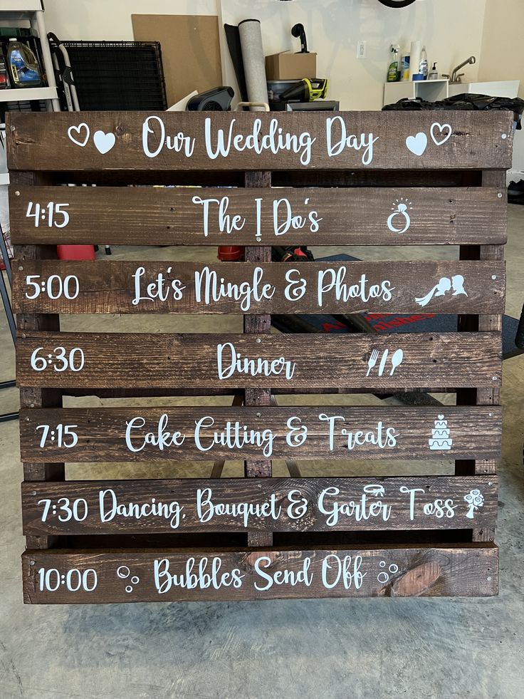 the wedding day sign is made out of pallet wood and has white writing on it