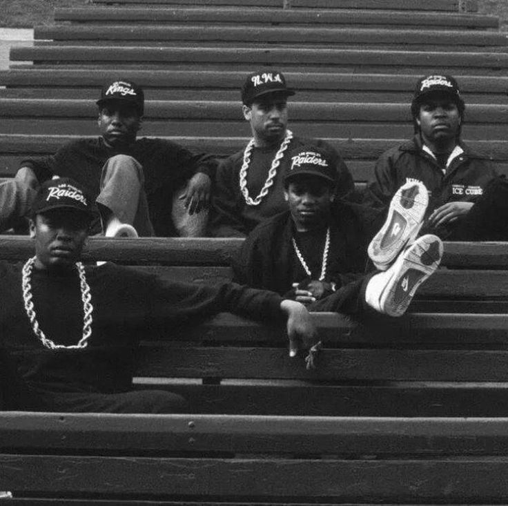 black men sitting on bleachers wearing hats and beads