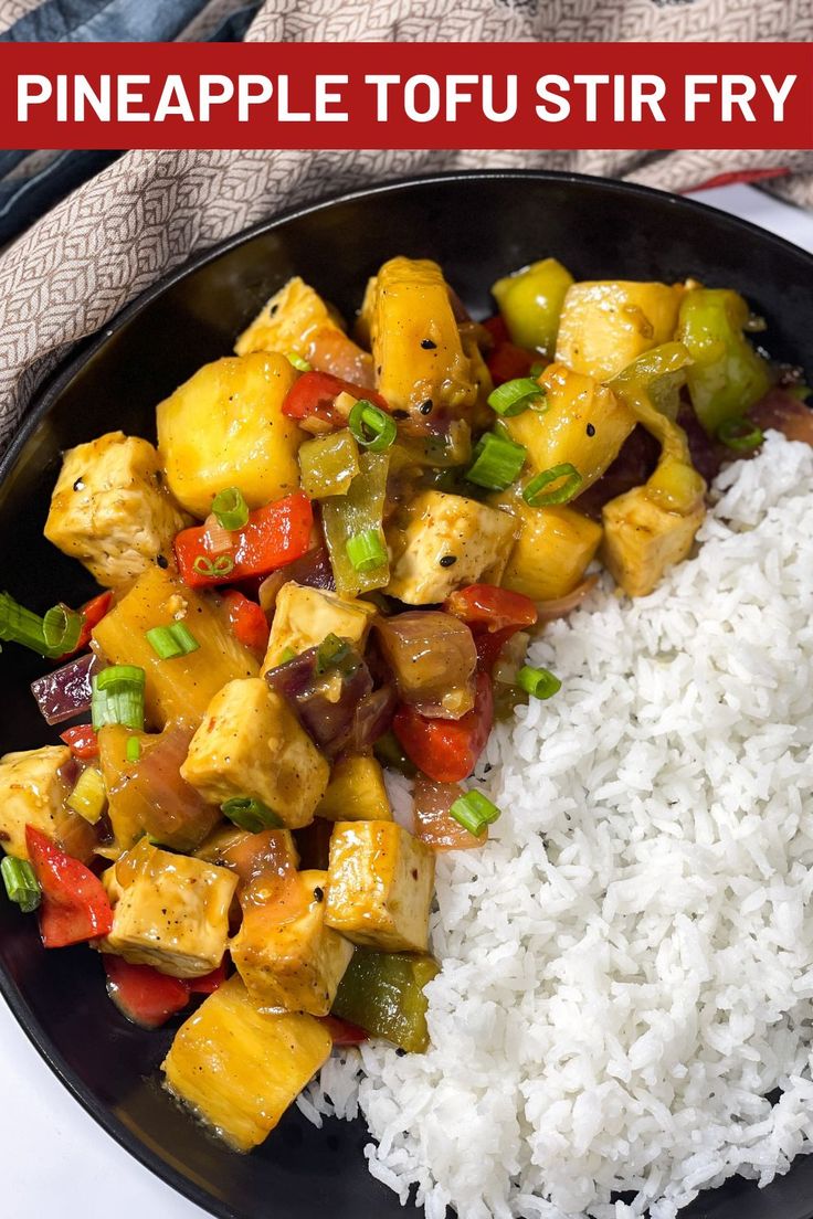 pineapple tofu stir fry with white rice on a black plate and red napkin