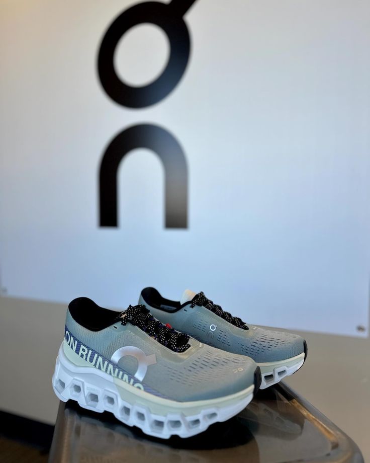 a pair of running shoes sitting on top of a glass table in front of a logo