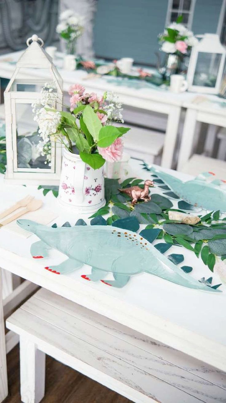 the table is decorated with flowers and green leaves, including an alligator - shaped vase